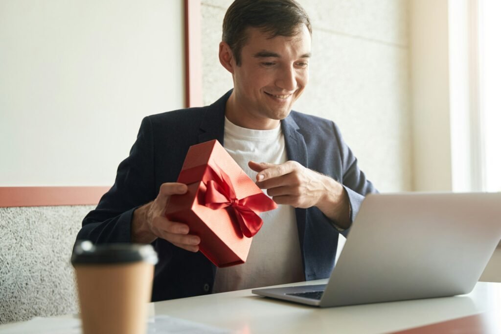 Male pointing to gift box for laptop camera